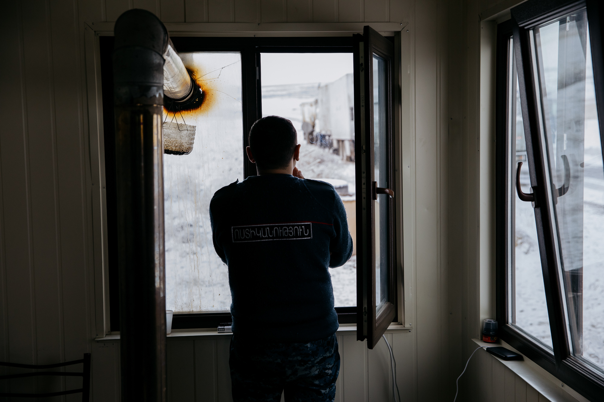 A police officer looks out from a hut at the Tegh checkpoint which acts as passport control for Nagorno-Karabakh. Tom Videlo/OC Media.